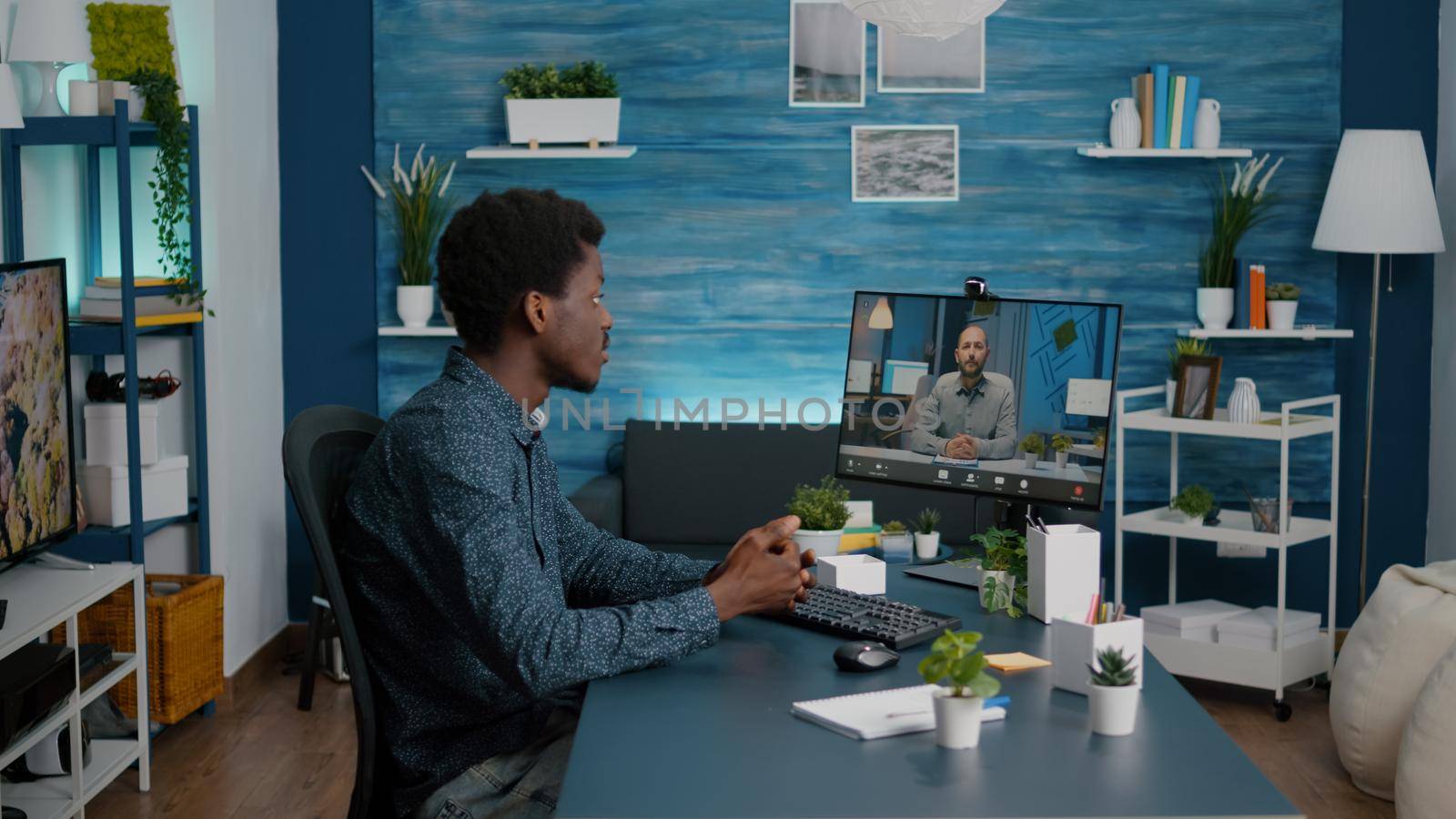 Remote black worker using internet web online communication to talk with his boss by DCStudio