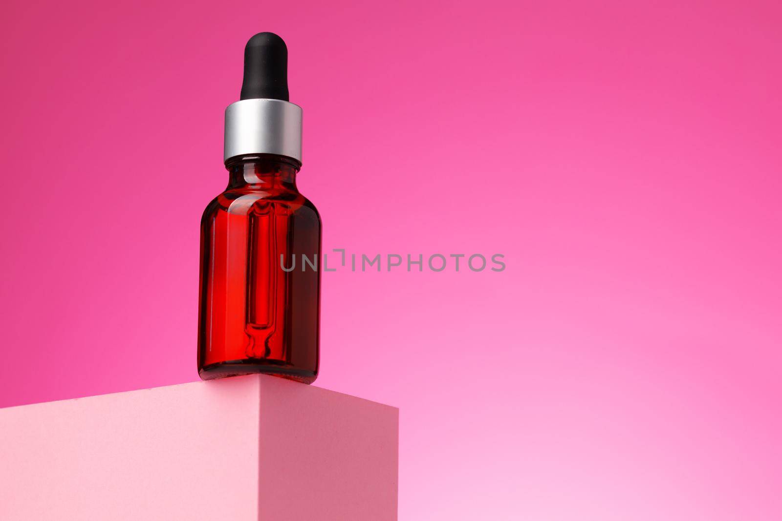 Beauty oil bottle with pipette against pink background close up