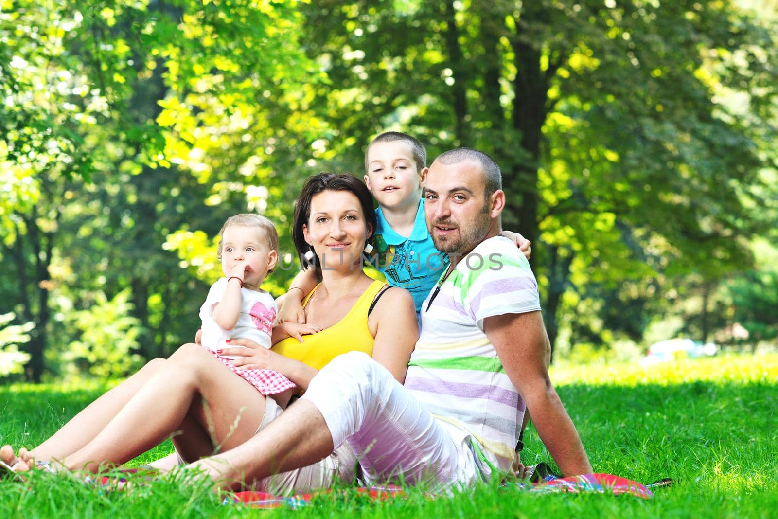 happy young couple with their children have fun at park by dotshock