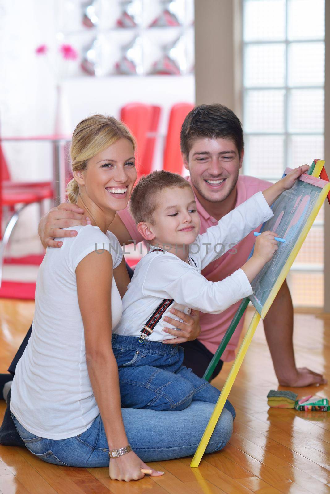 happy young family teach leassons and prepare their son for school while draw on board at home