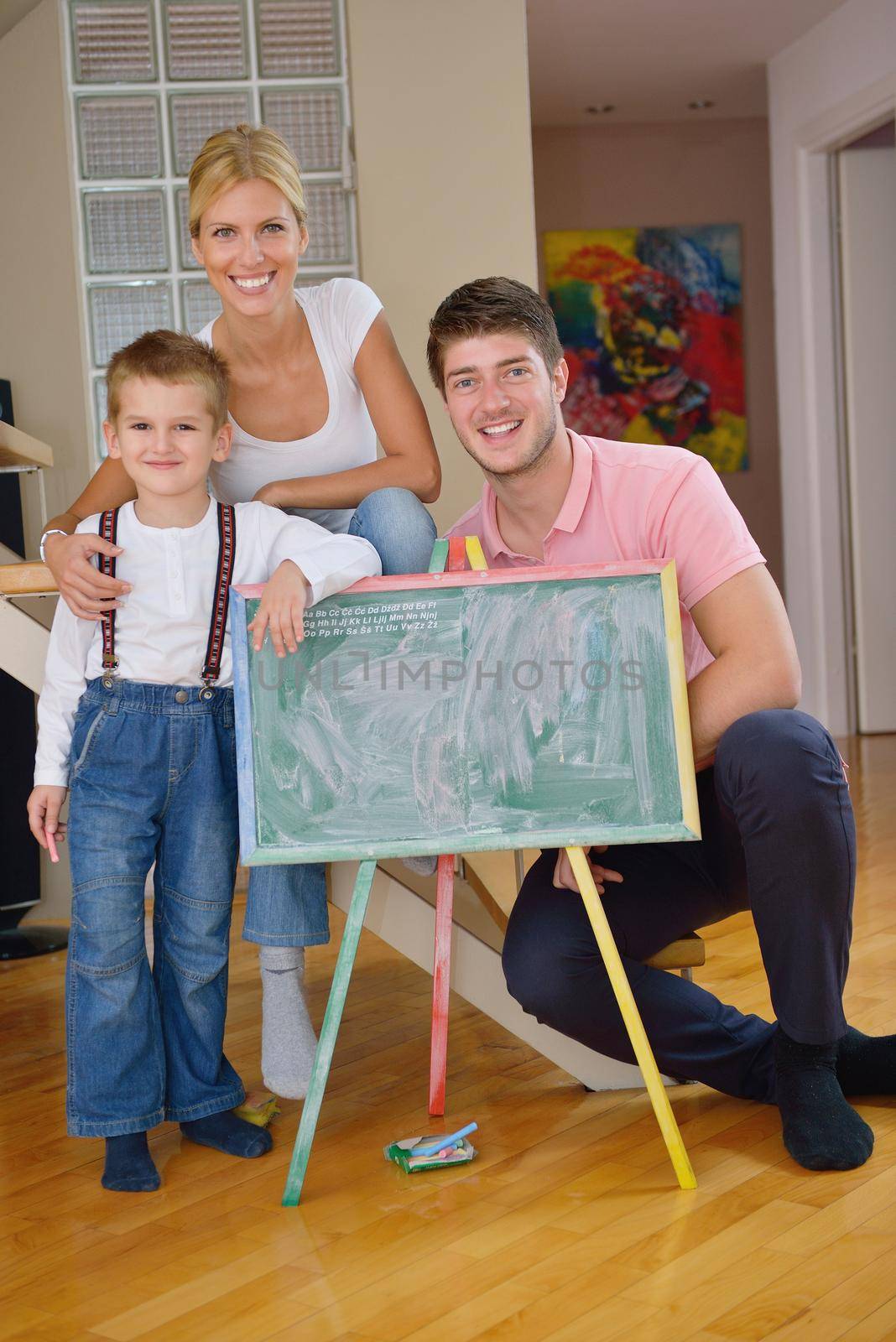 happy young family teach leassons and prepare their son for school while draw on board at home