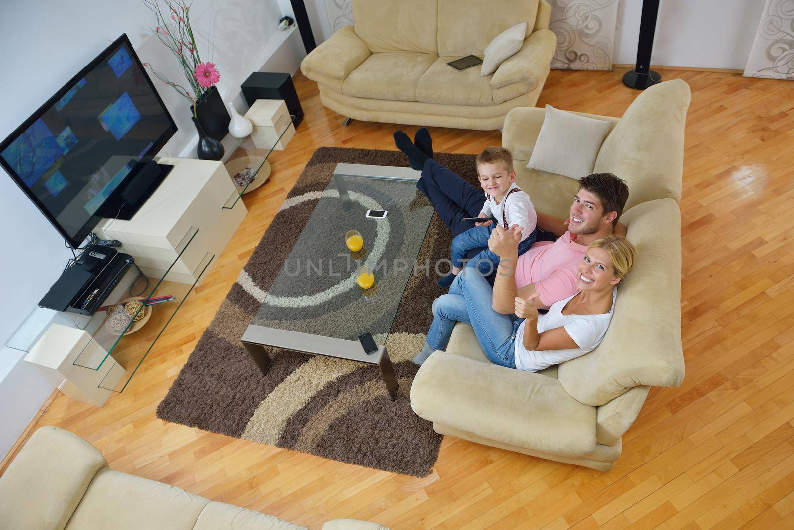 happy young family with kids in bright modern living room have fun and looking big flat lcd tv