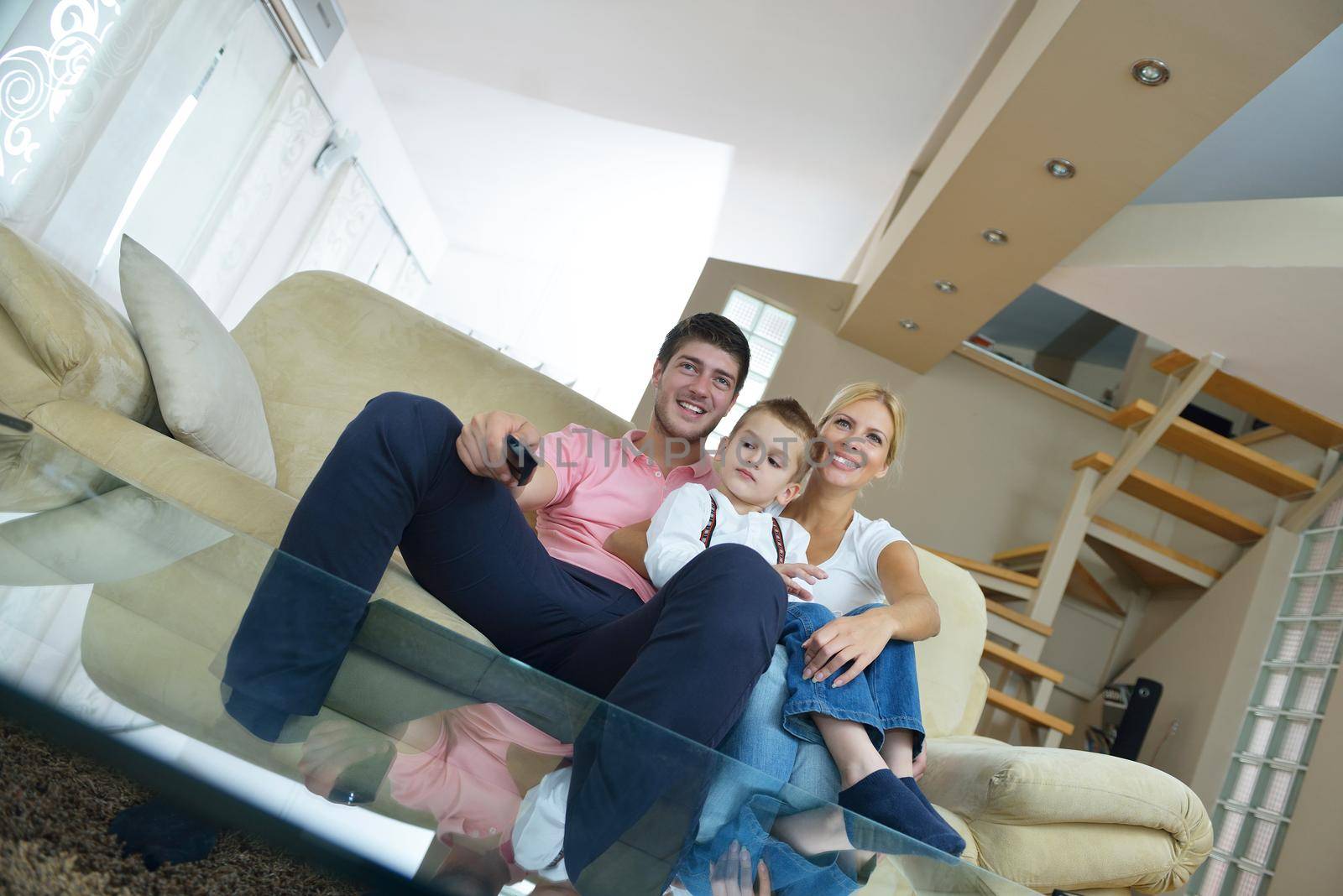 happy young family with kids in bright modern living room have fun and looking big flat lcd tv