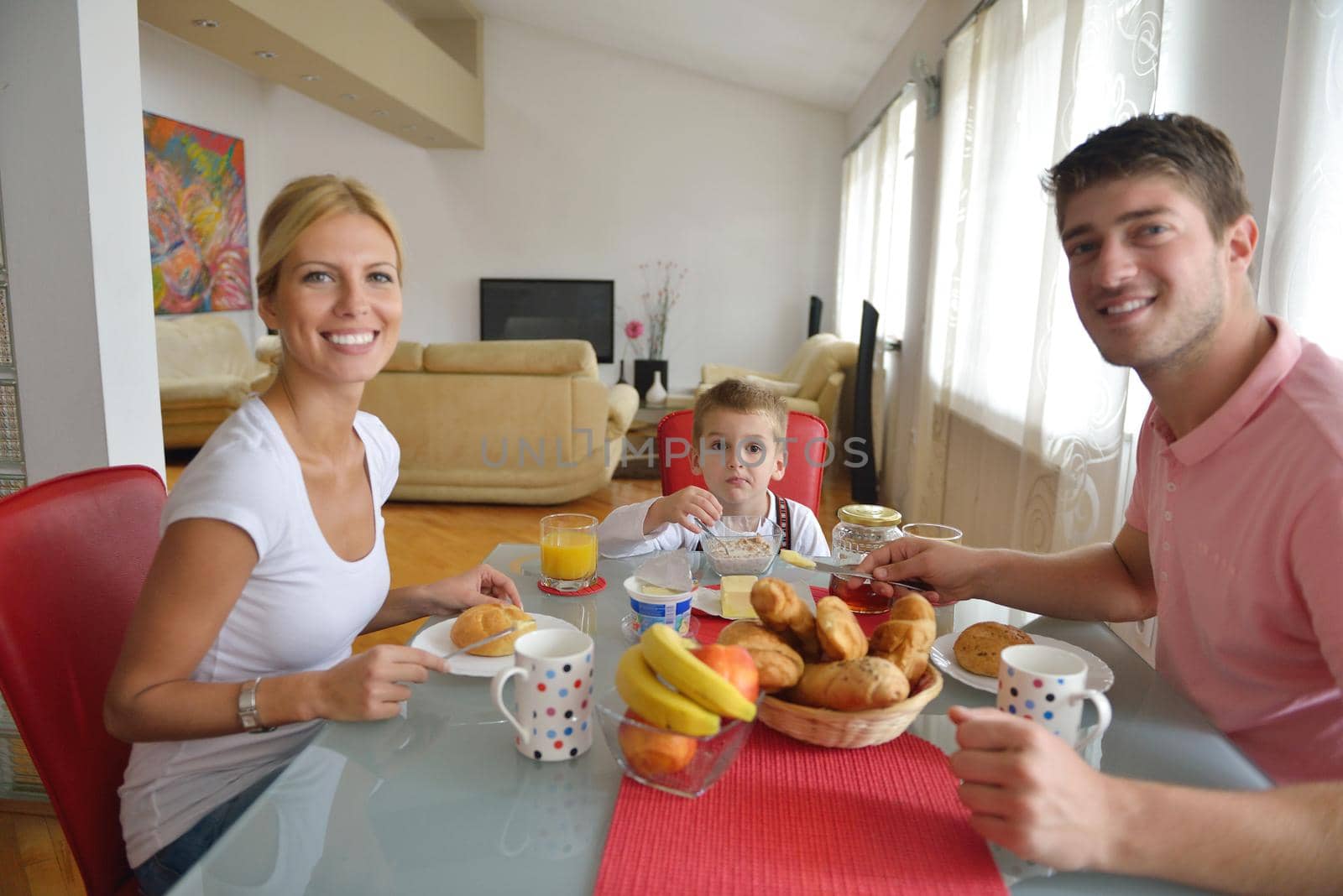 happy young family have healthy breakfast at kitchen with red details on bright morning light