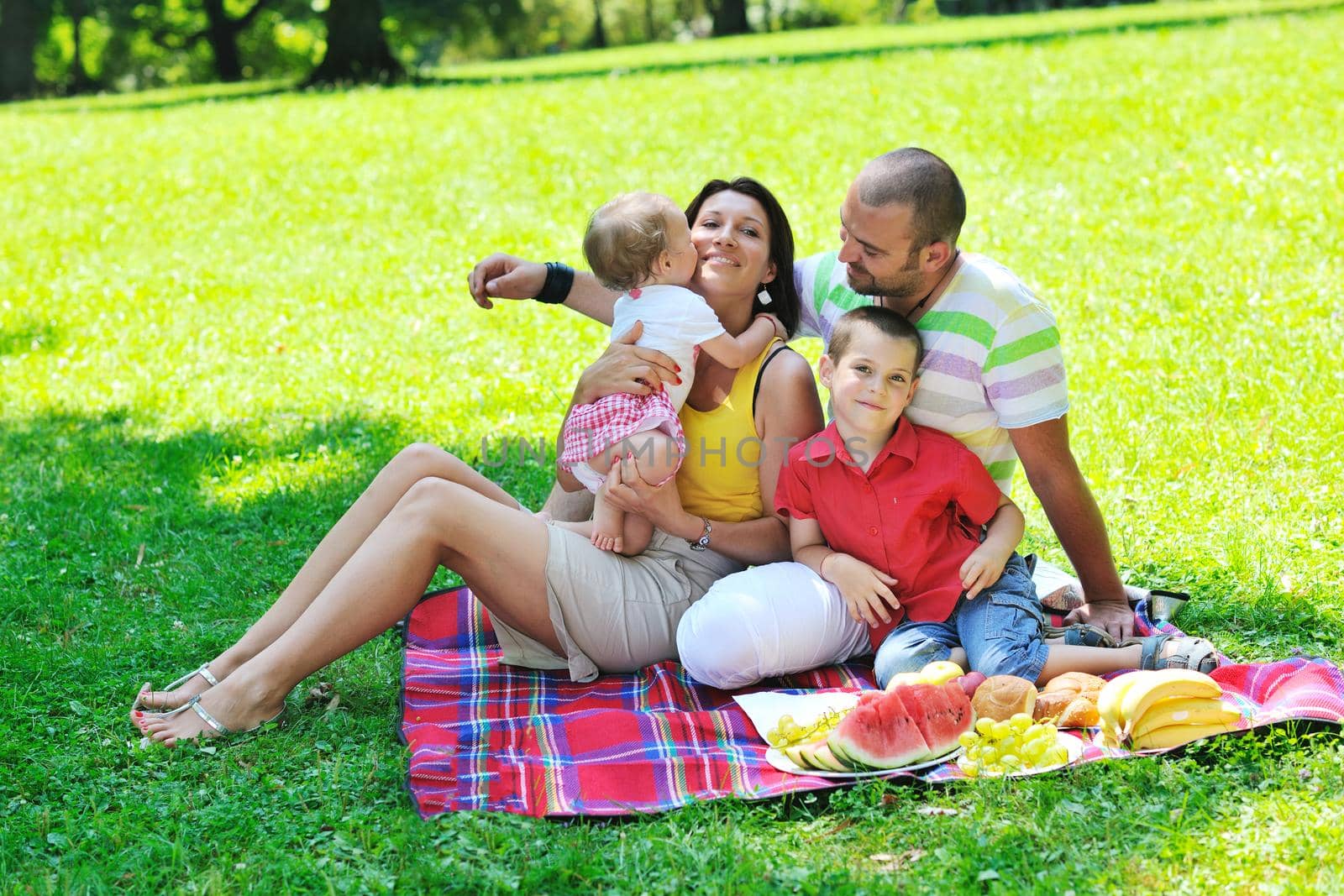 happy young couple with their children have fun at beautiful park outdoor in nature