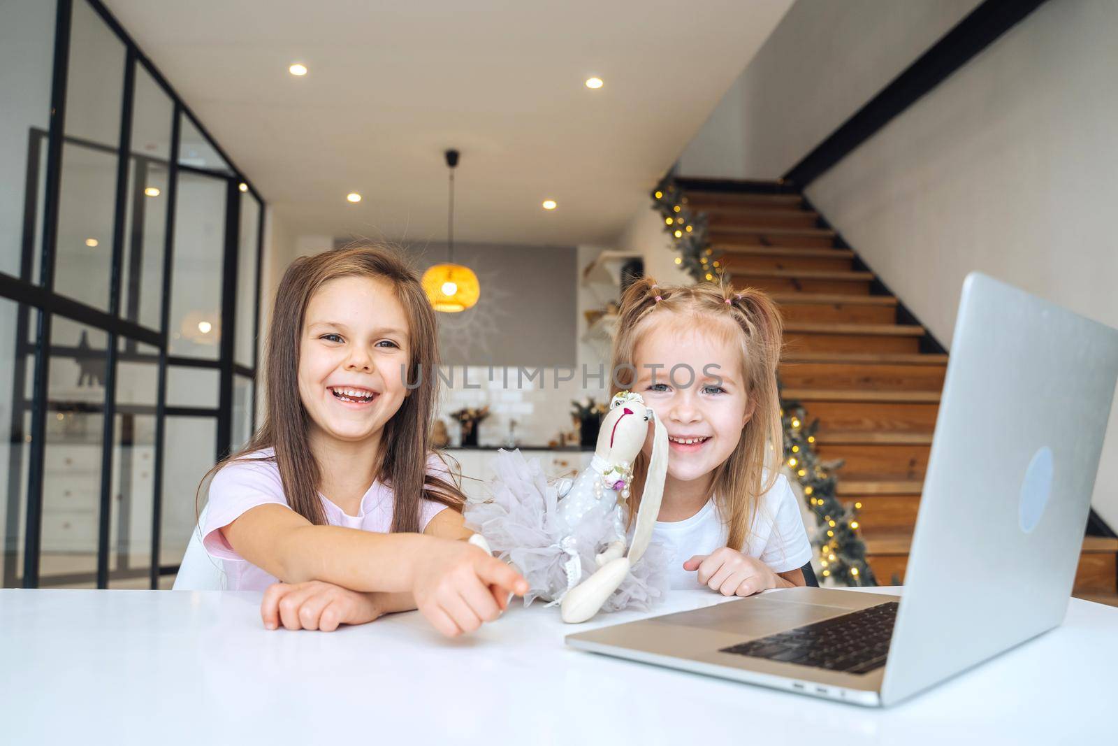 Two little girls playing together at the laptop while sitting