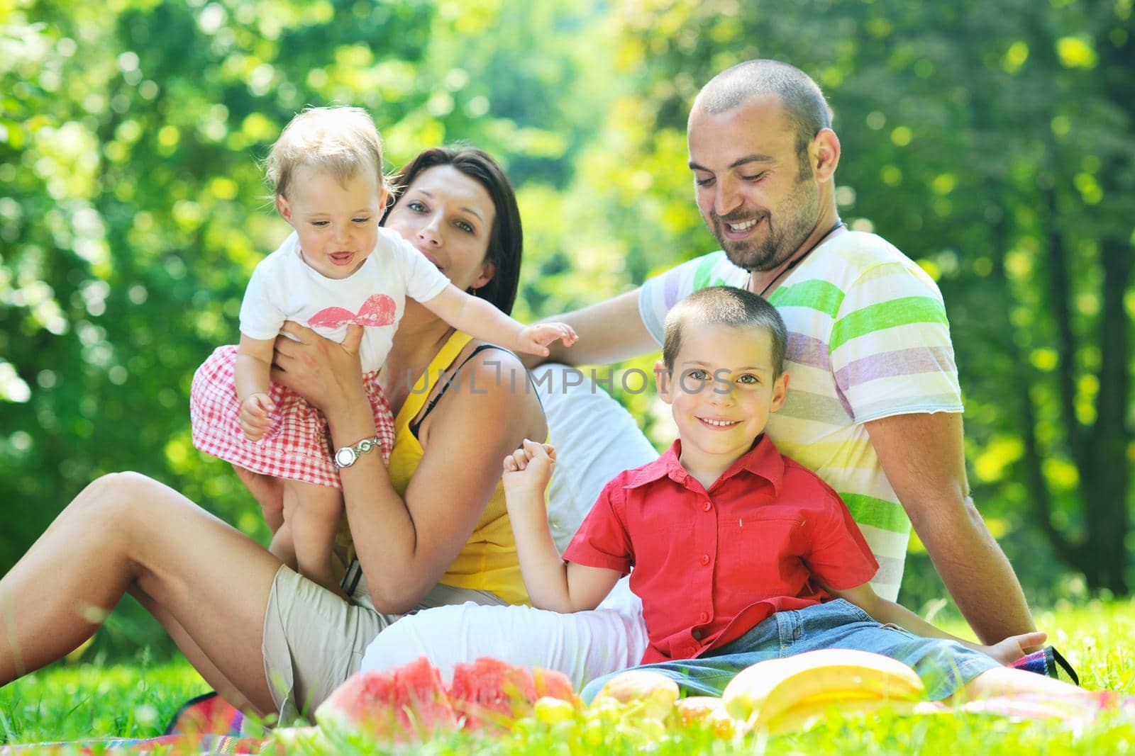 happy young couple with their children have fun at beautiful park outdoor in nature