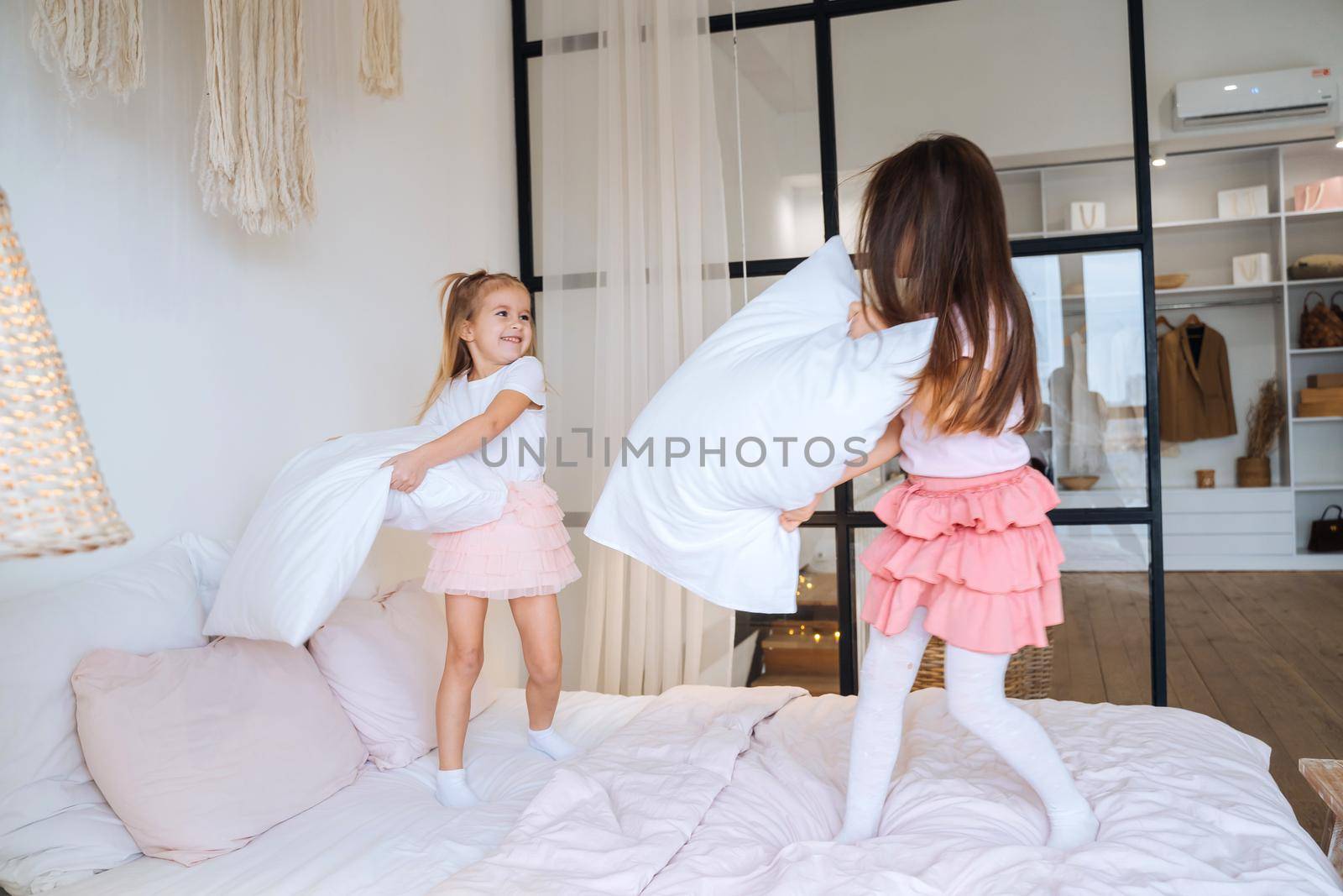 two girls playing with pillows in bedroom
