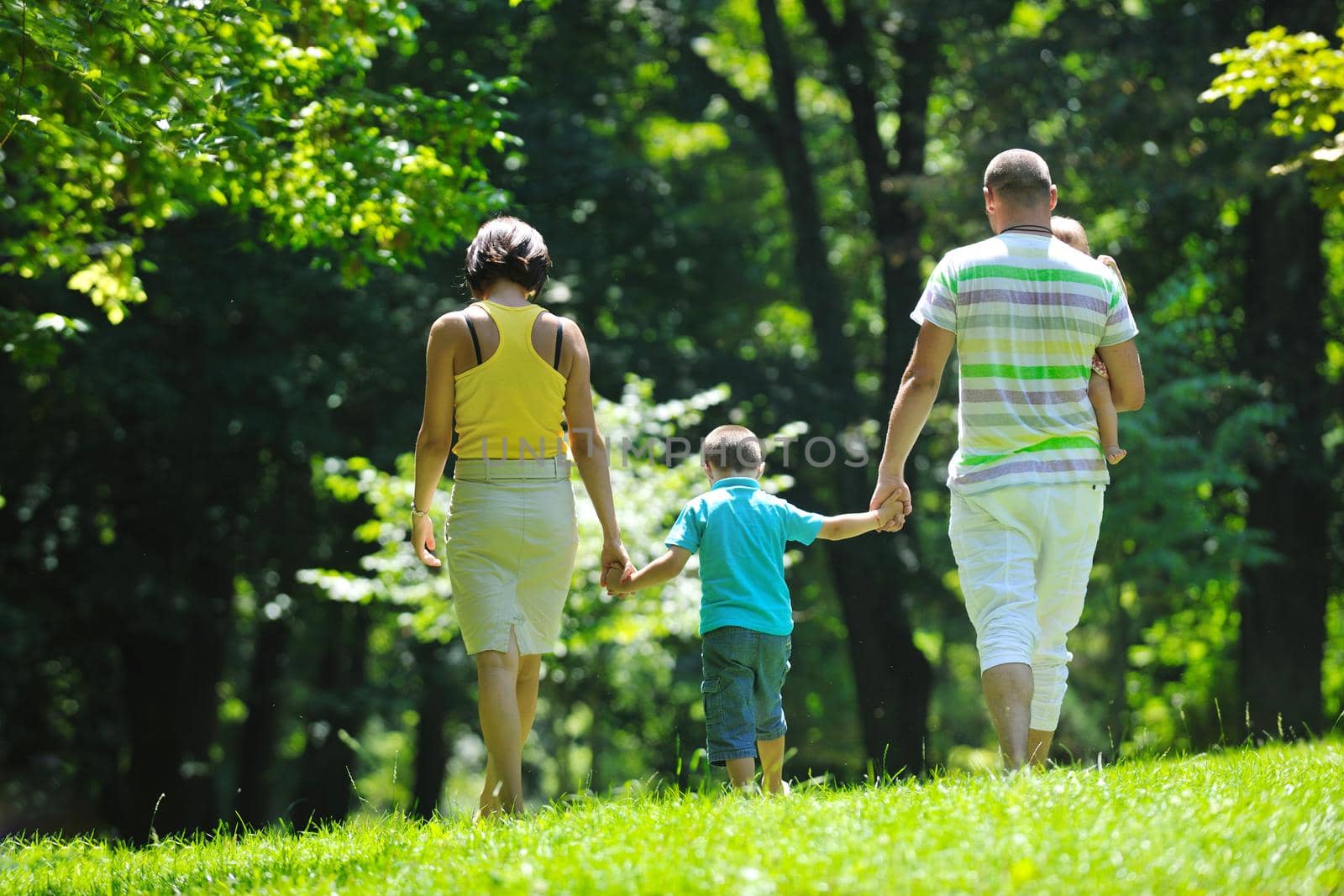 happy young couple with their children have fun at beautiful park outdoor in nature