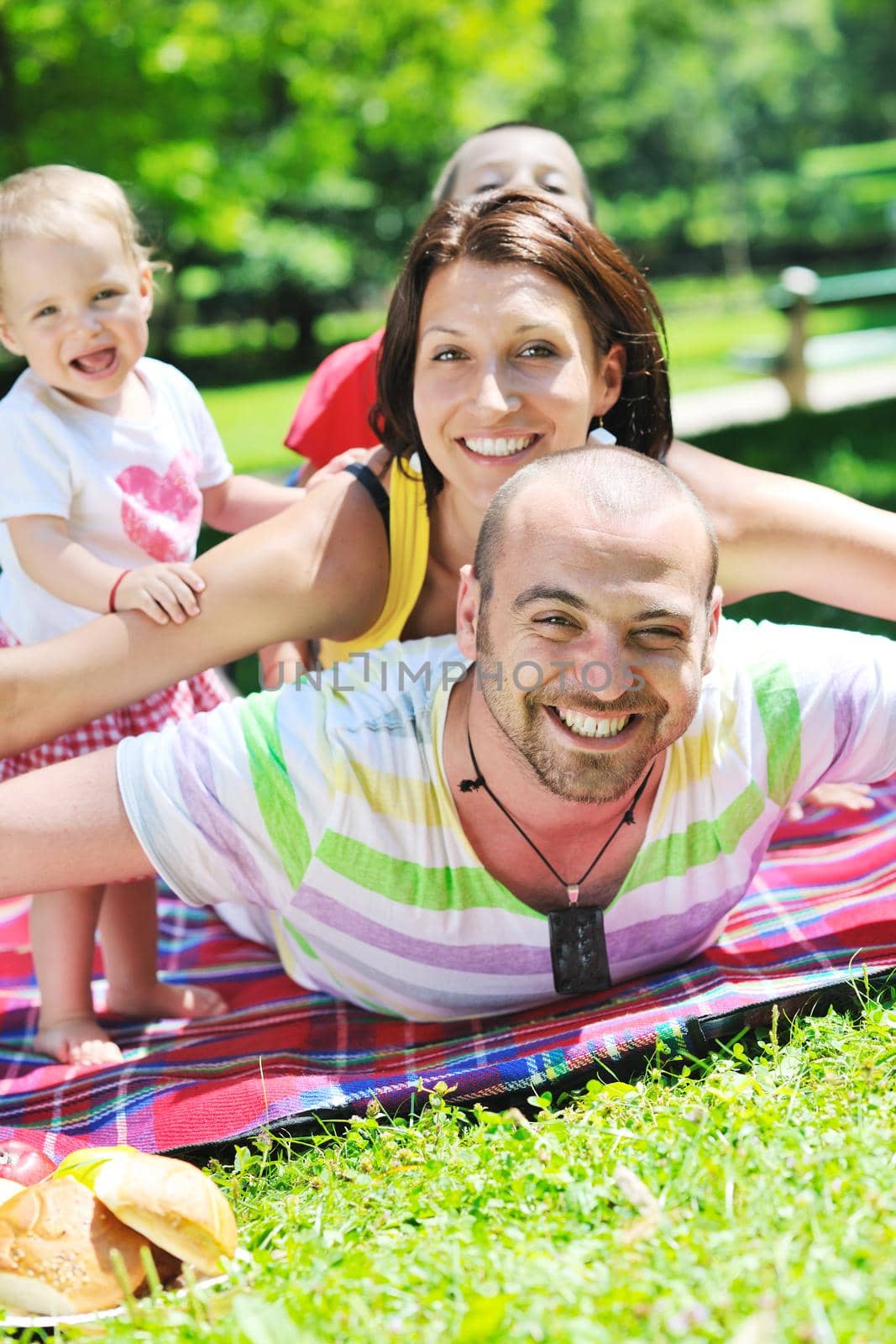 happy young couple with their children have fun at beautiful park outdoor in nature