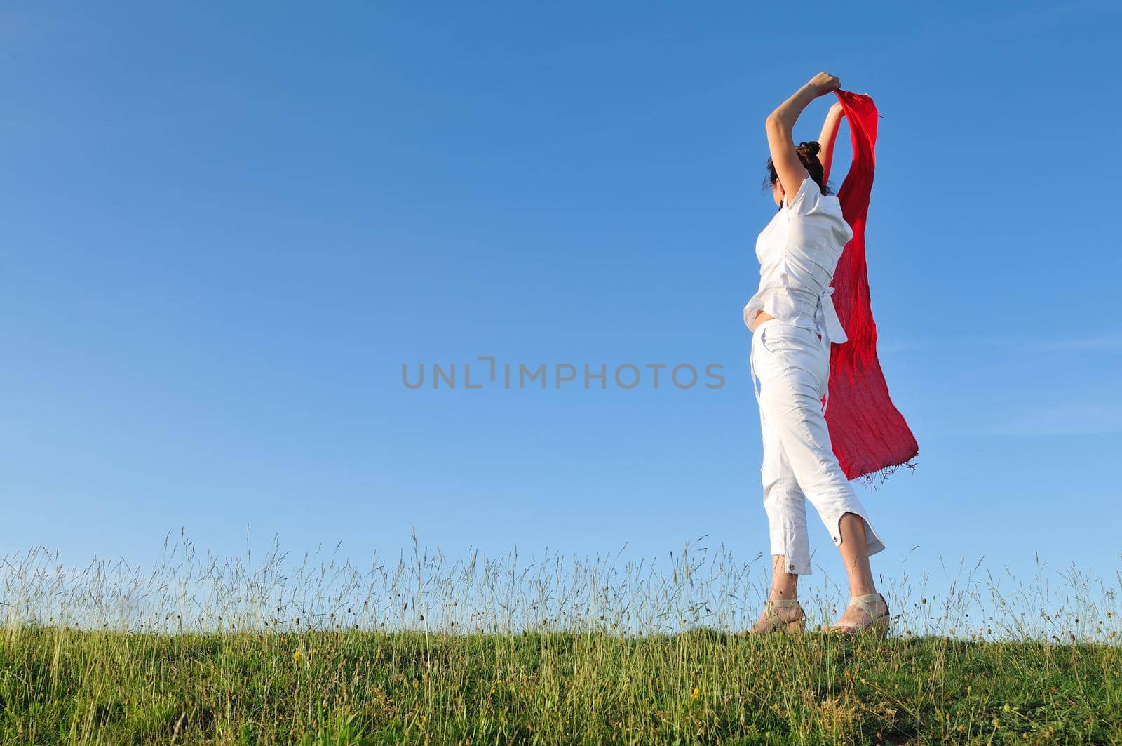 beautiful woman with red scarf on meadow by dotshock