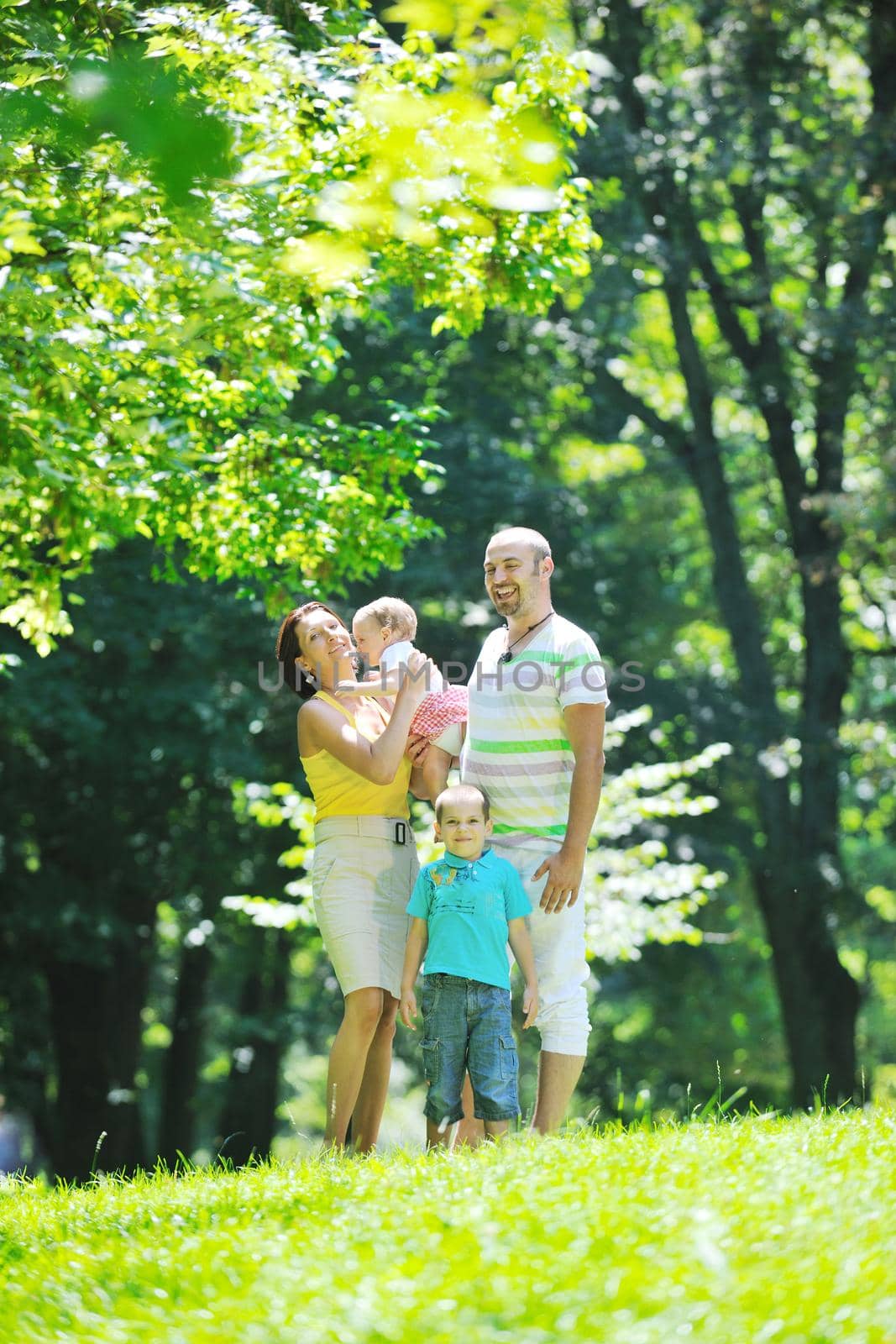 happy young couple with their children have fun at beautiful park outdoor in nature