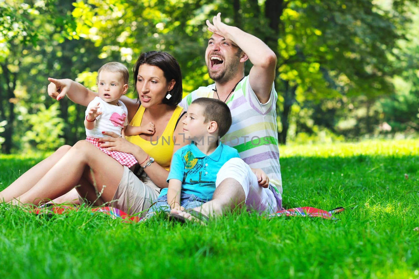 happy young couple with their children have fun at beautiful park outdoor in nature