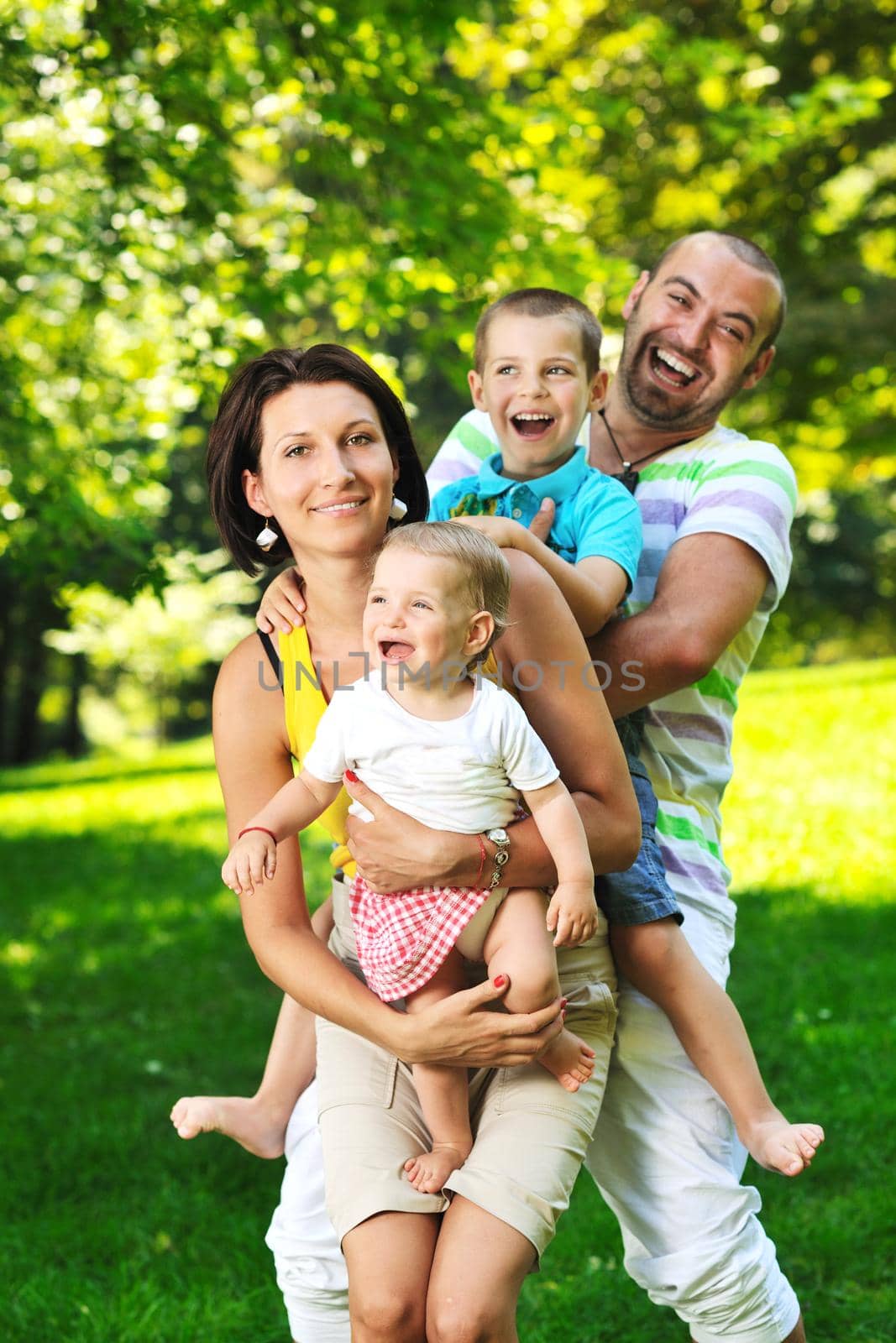 happy young couple with their children have fun at beautiful park outdoor in nature