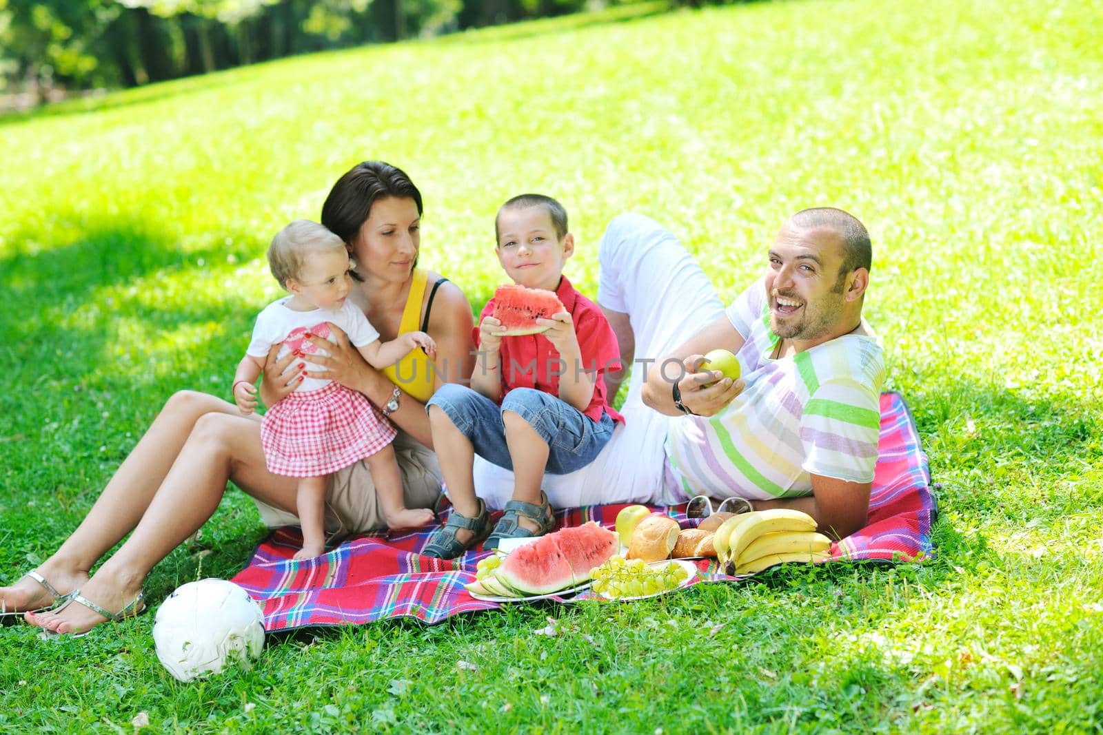 happy young couple with their children have fun at beautiful park outdoor in nature