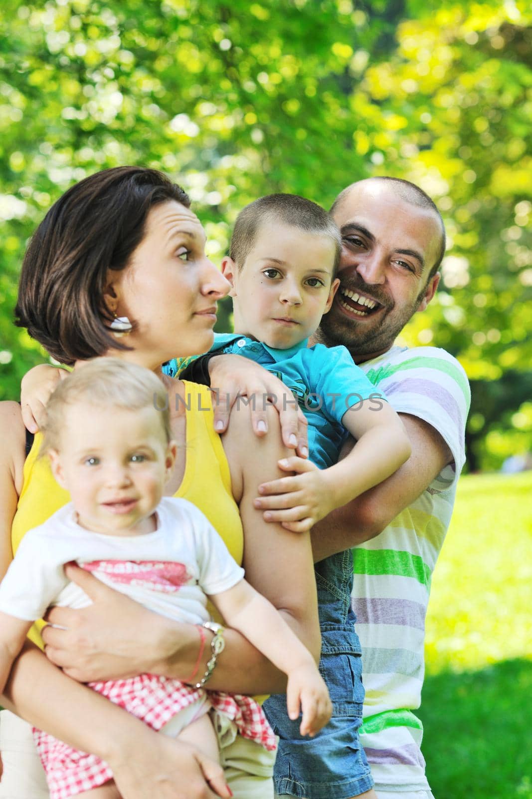 happy young couple with their children have fun at beautiful park outdoor in nature