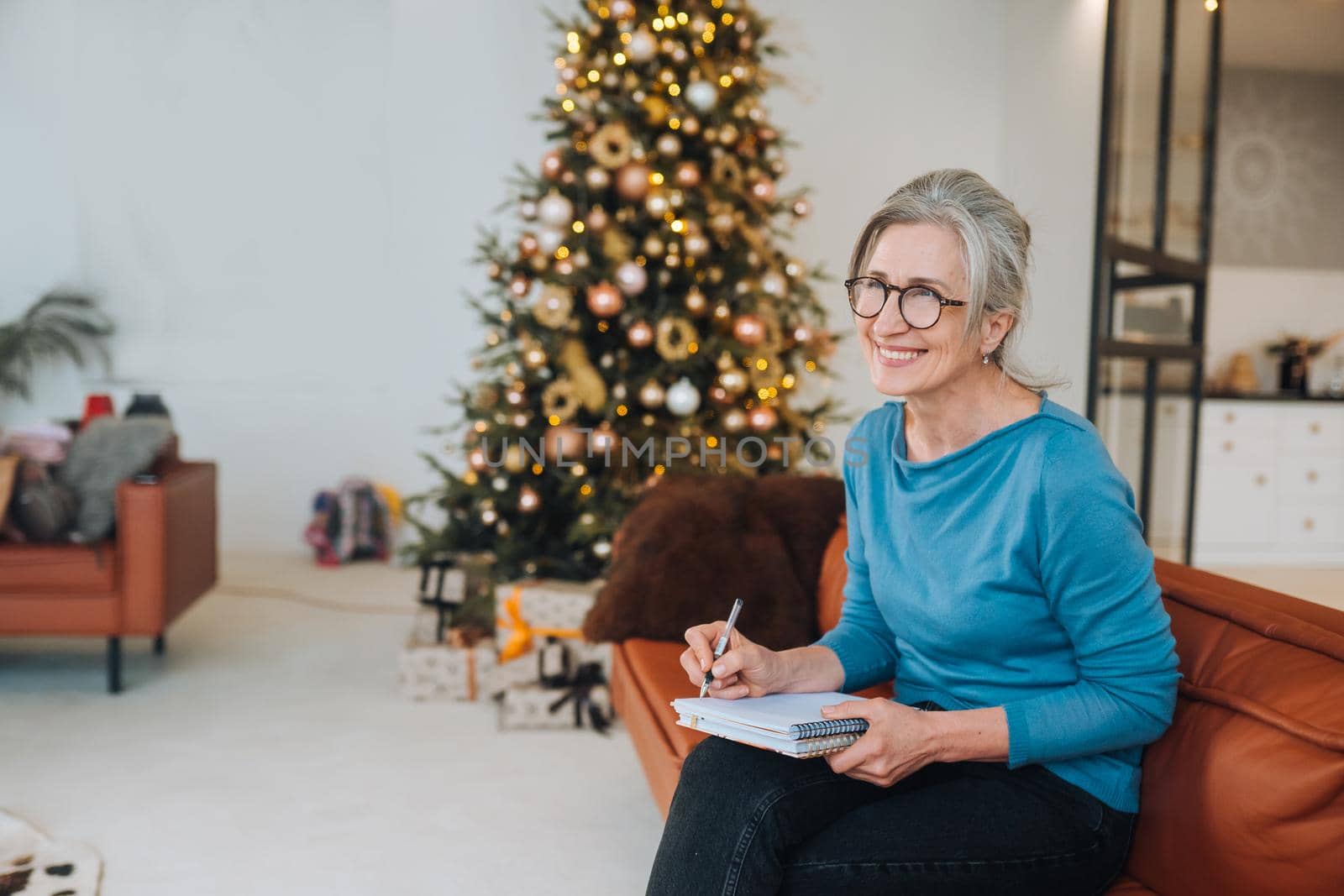 Grandma sits on the couch writing something in a note at home