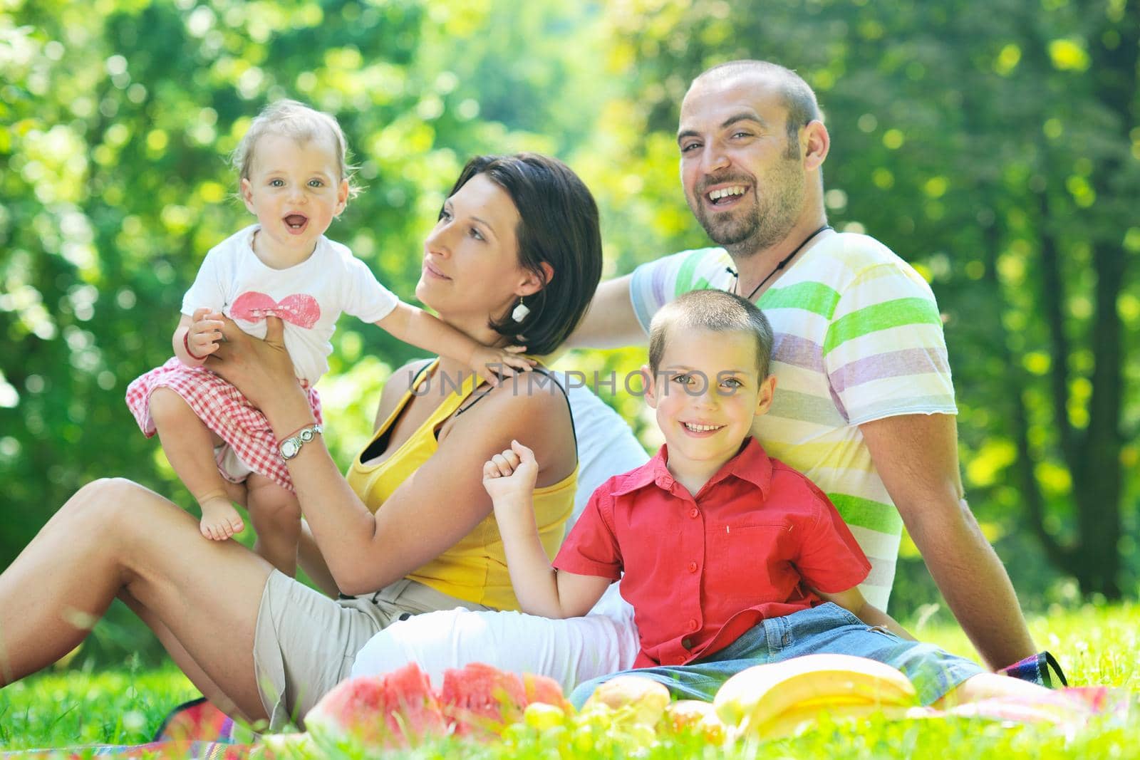 happy young couple with their children have fun at beautiful park outdoor in nature