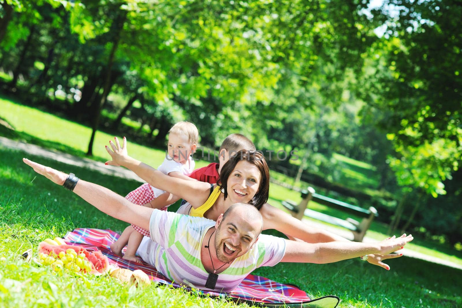 happy young couple with their children have fun at beautiful park outdoor in nature