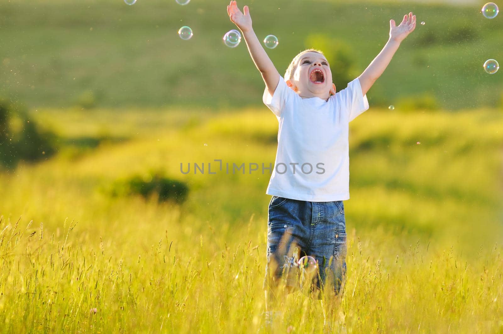 happy young beautiful child have fun on eadow with soap bubbles toy