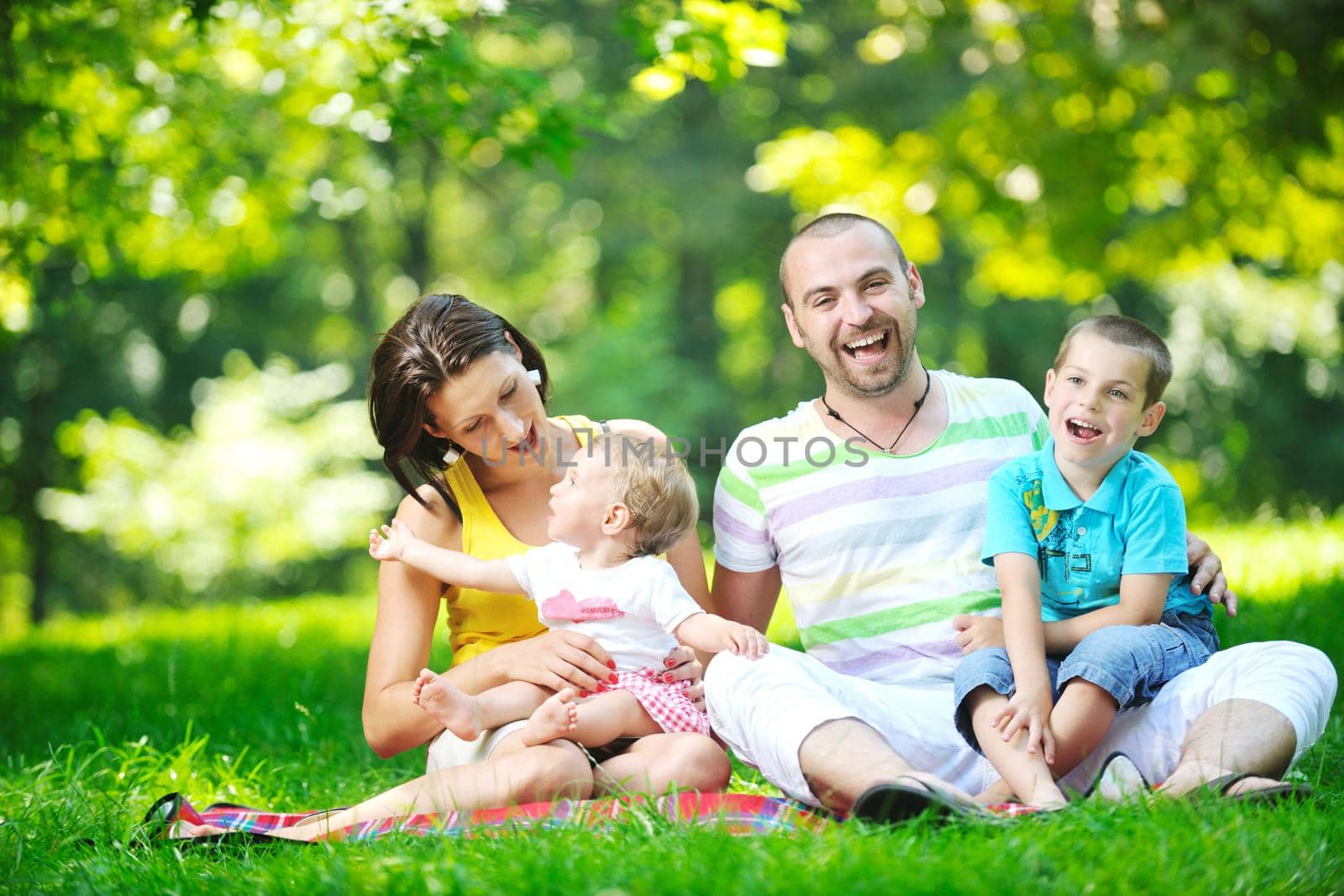 happy young couple with their children have fun at park by dotshock