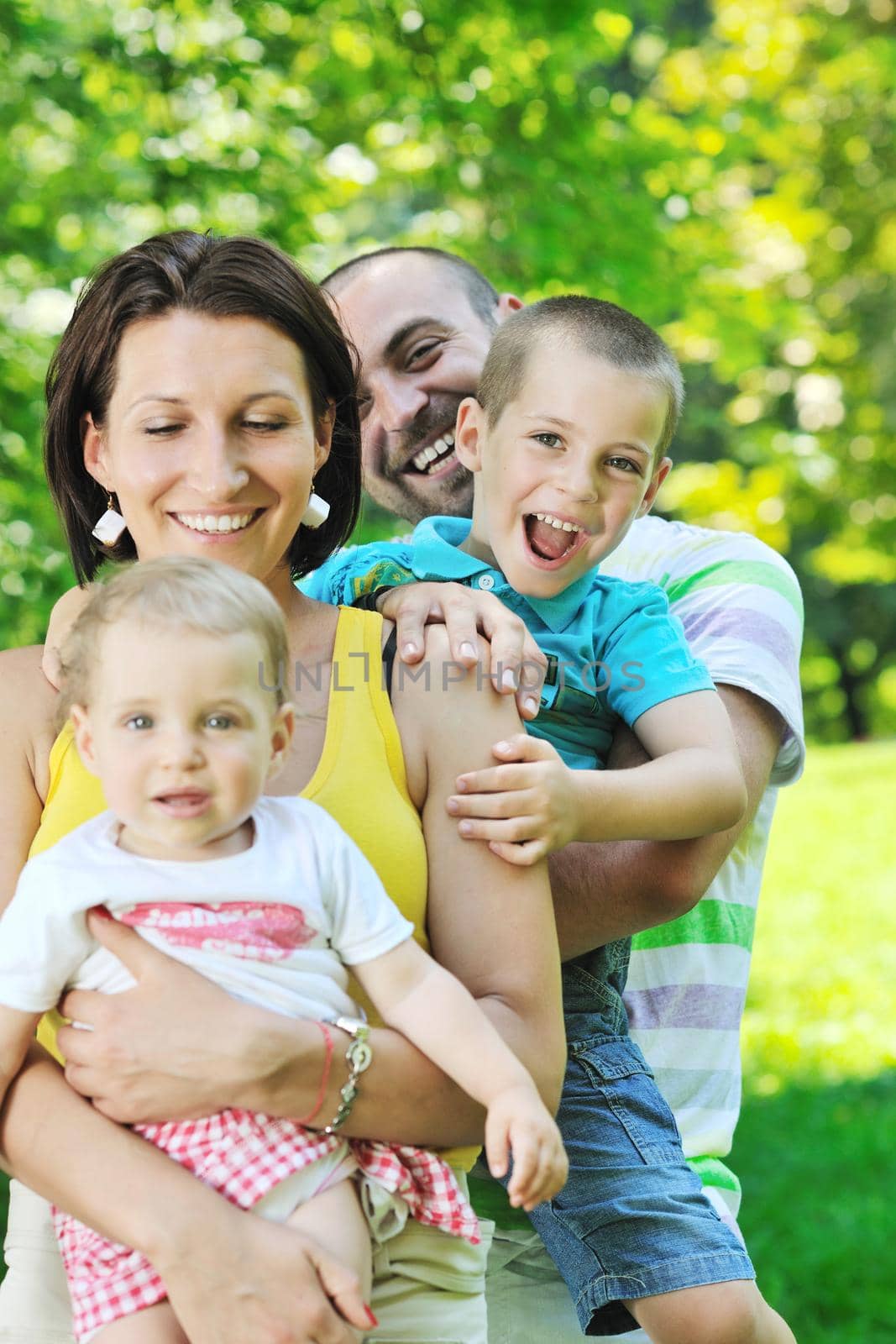 happy young couple with their children have fun at beautiful park outdoor in nature