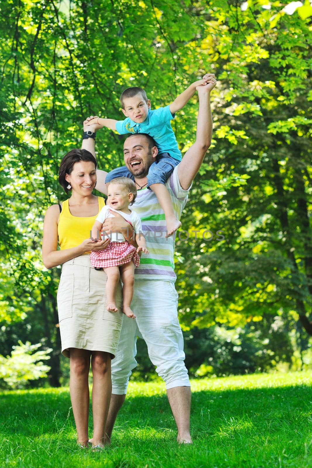 happy young couple with their children have fun at beautiful park outdoor in nature