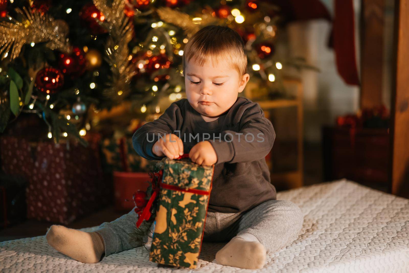 Child celebrating holidays near Christmas tree. New year and gifts. Magic.