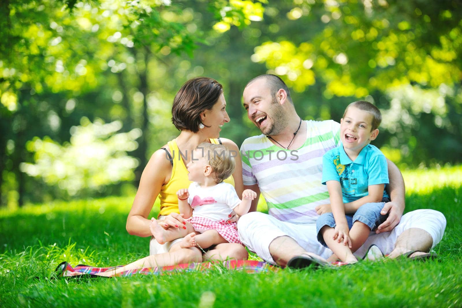 happy young couple with their children have fun at park by dotshock