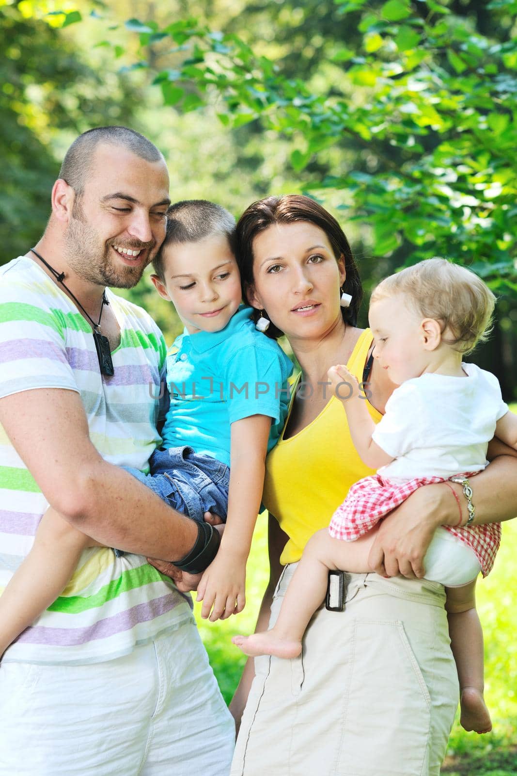 happy young couple with their children have fun at park by dotshock