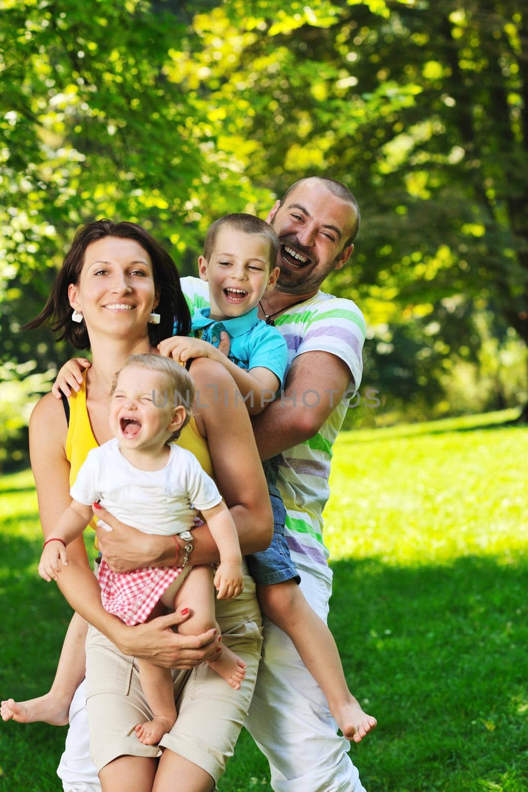 happy young couple with their children have fun at beautiful park outdoor in nature