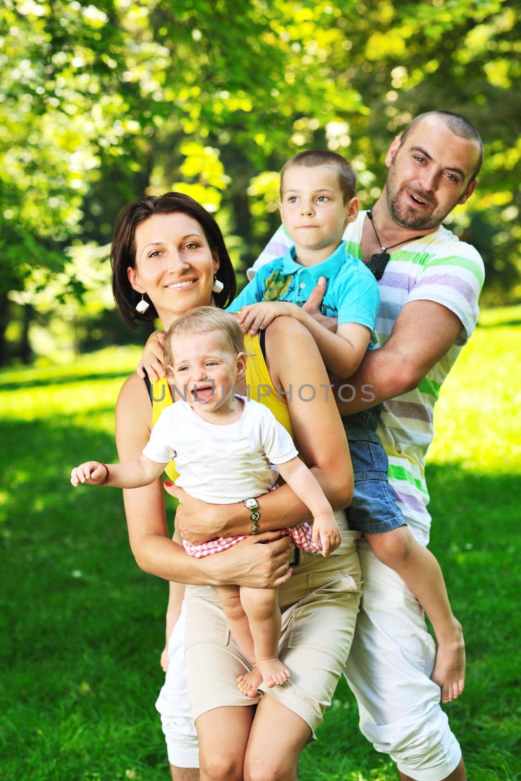 happy young couple with their children have fun at beautiful park outdoor in nature