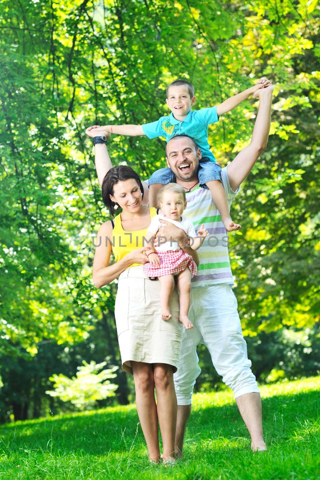 happy young couple with their children have fun at beautiful park outdoor in nature