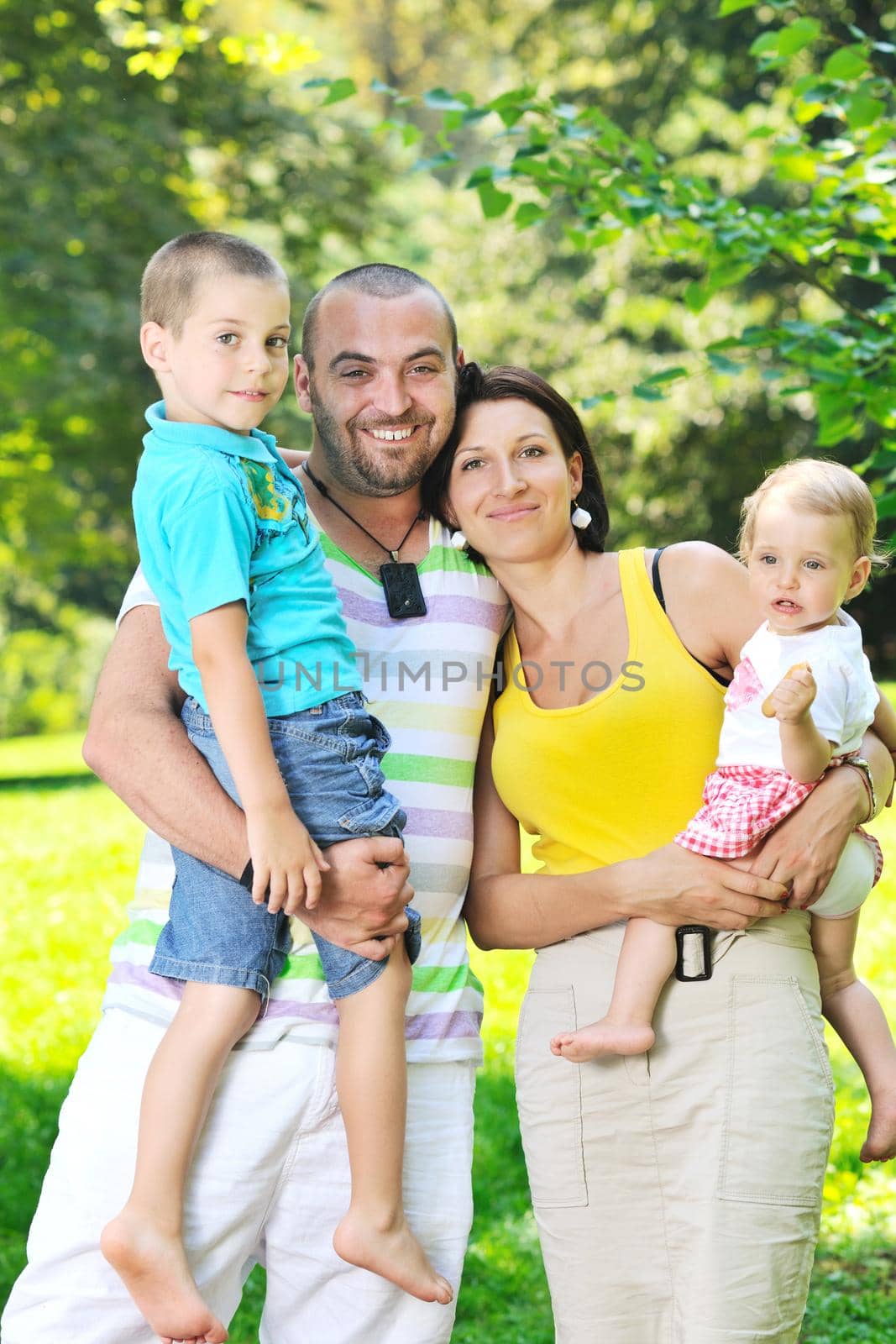 happy young couple with their children have fun at beautiful park outdoor in nature