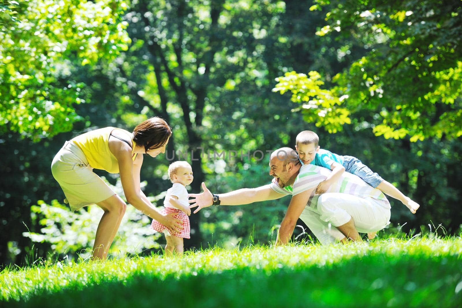 happy young couple with their children have fun at beautiful park outdoor in nature