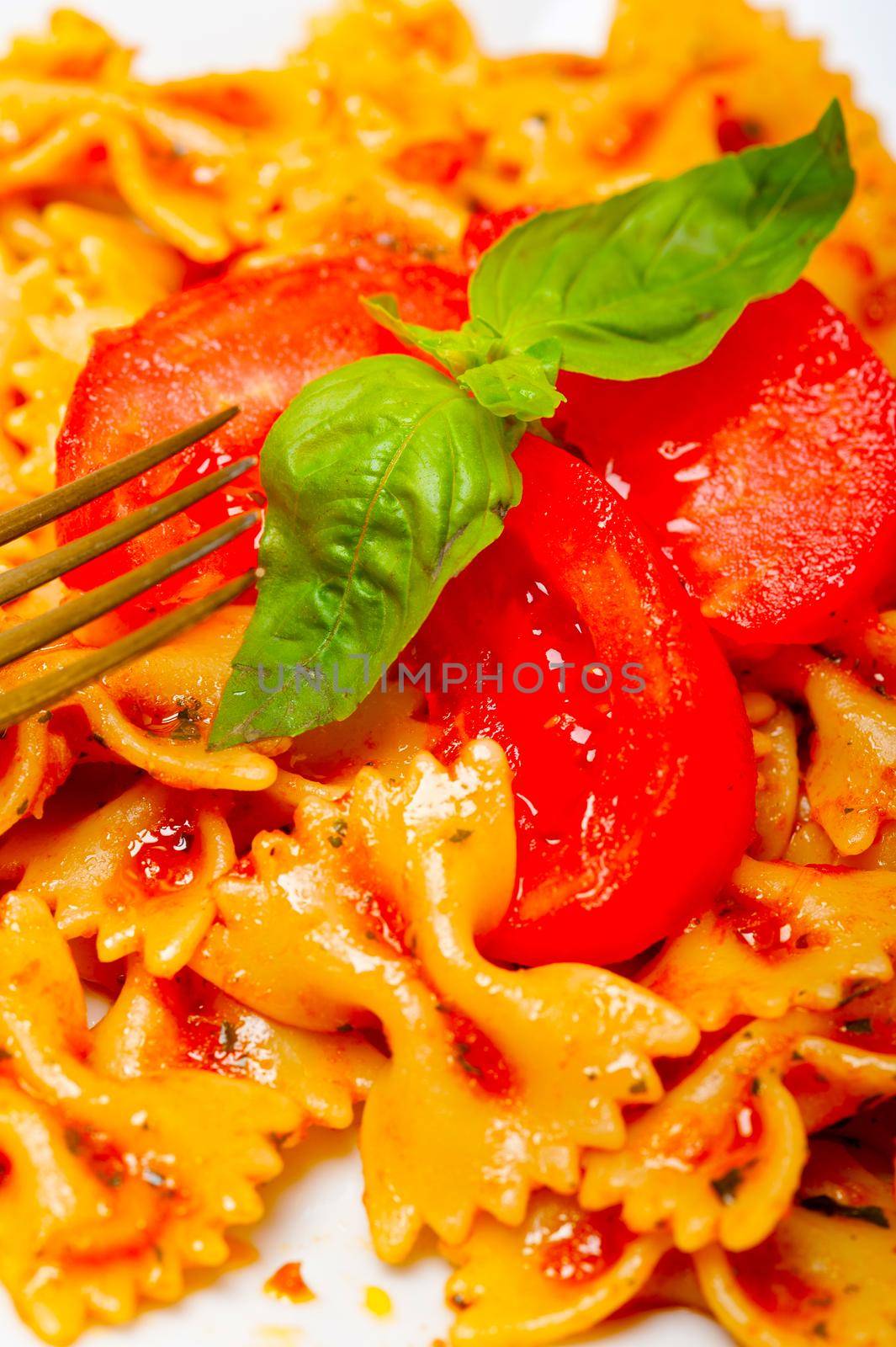 Italian pasta farfalle butterfly bow-tie with tomato basil sauce over white rustic wood table