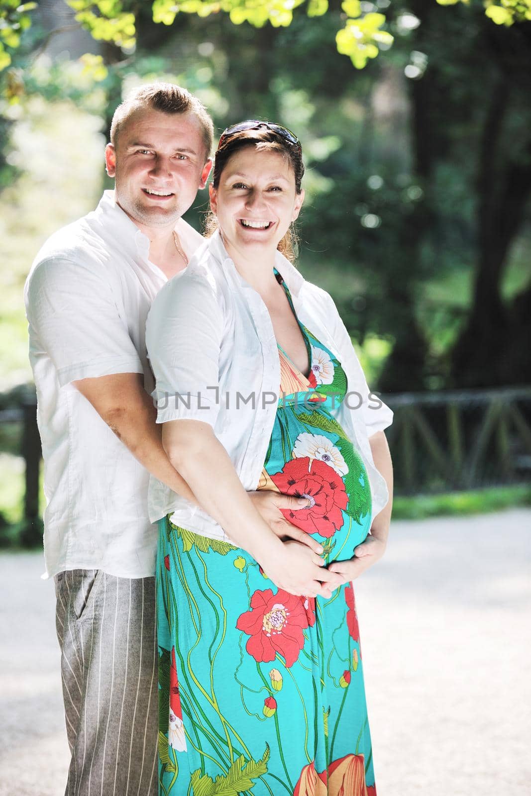 Happy pregnant couple have fun and romantic time at beautiful sunny day in park