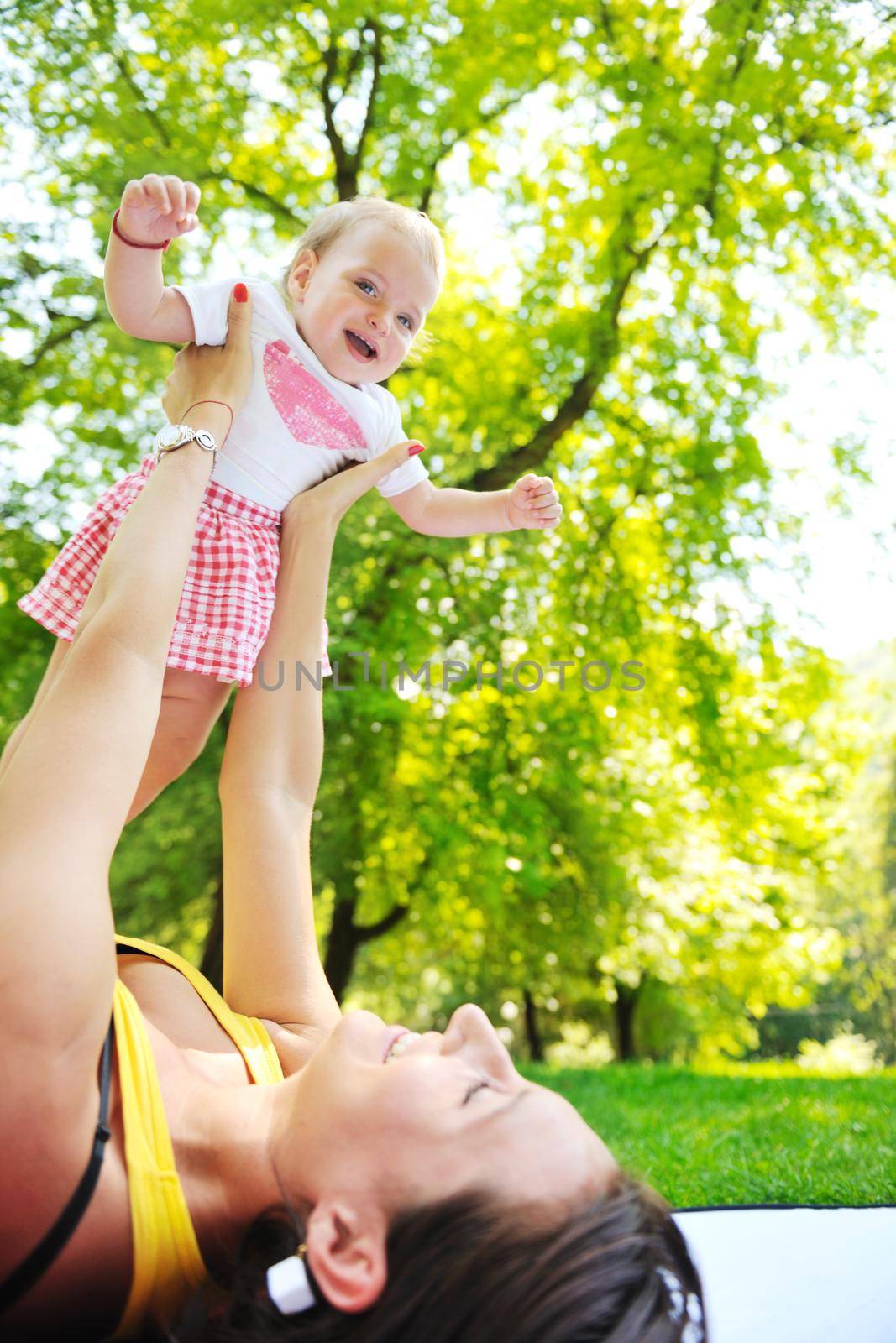 happy young woman and baby have fun while playing in beautiful bright park at summer season