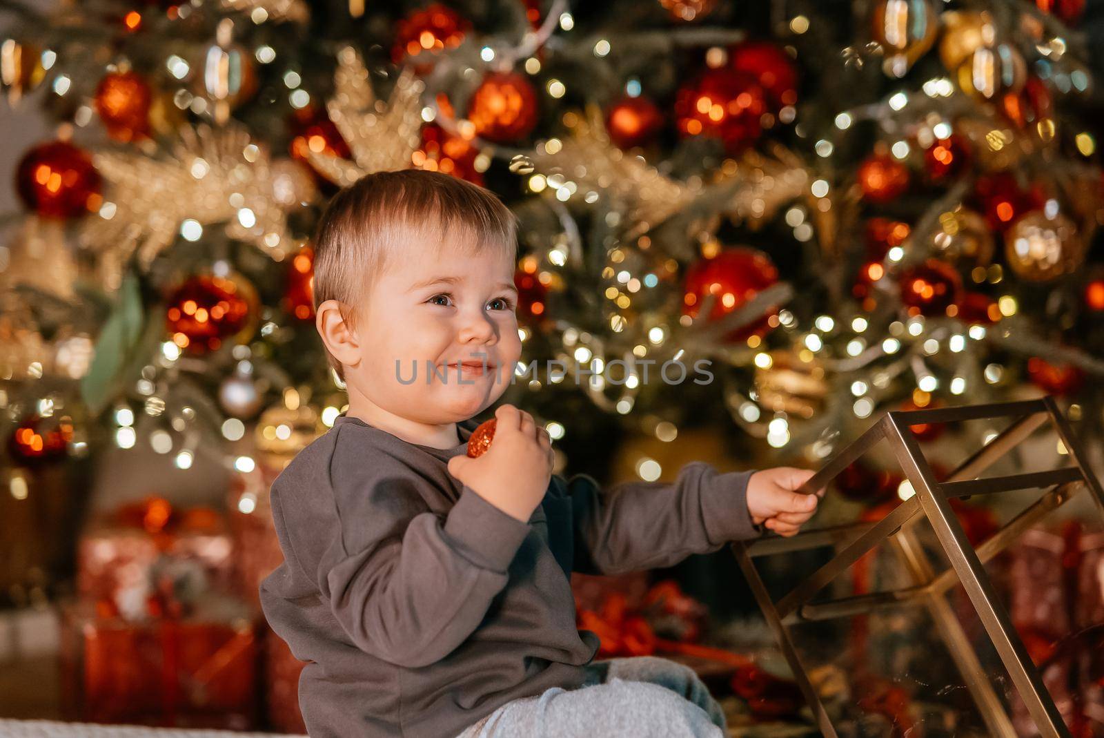 Little boy playing by the christmas tree by teksomolika