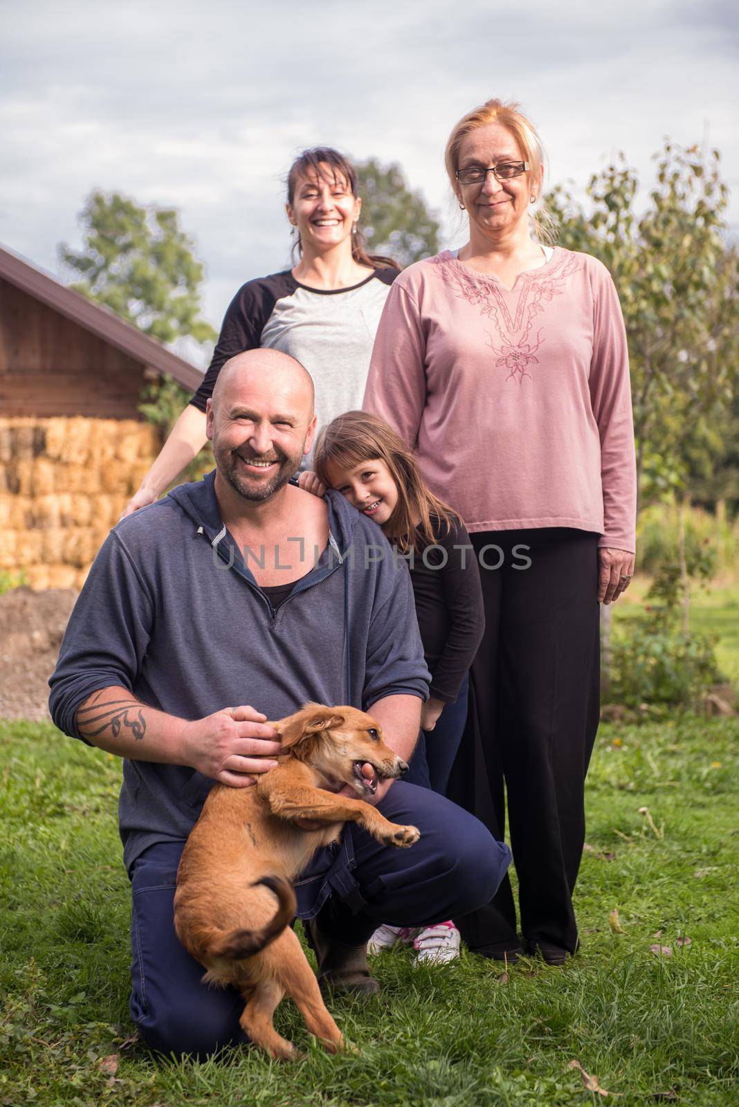 portrait of happy three generations family with dog at beautiful countryside farm