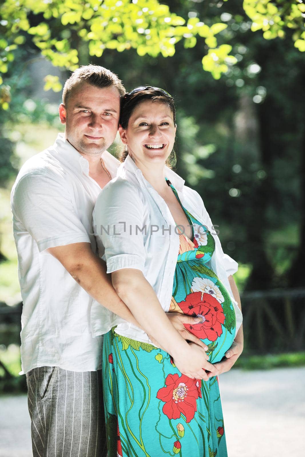 Happy pregnant couple at beautiful sunny day in park by dotshock