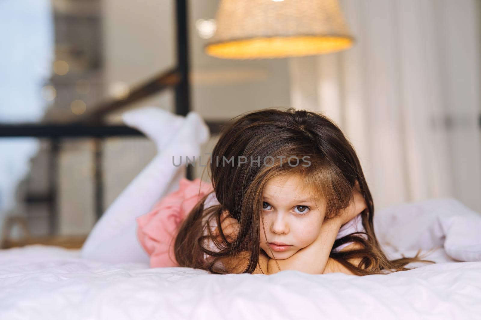 Beautiful little girl lying in the bed looking at the camera