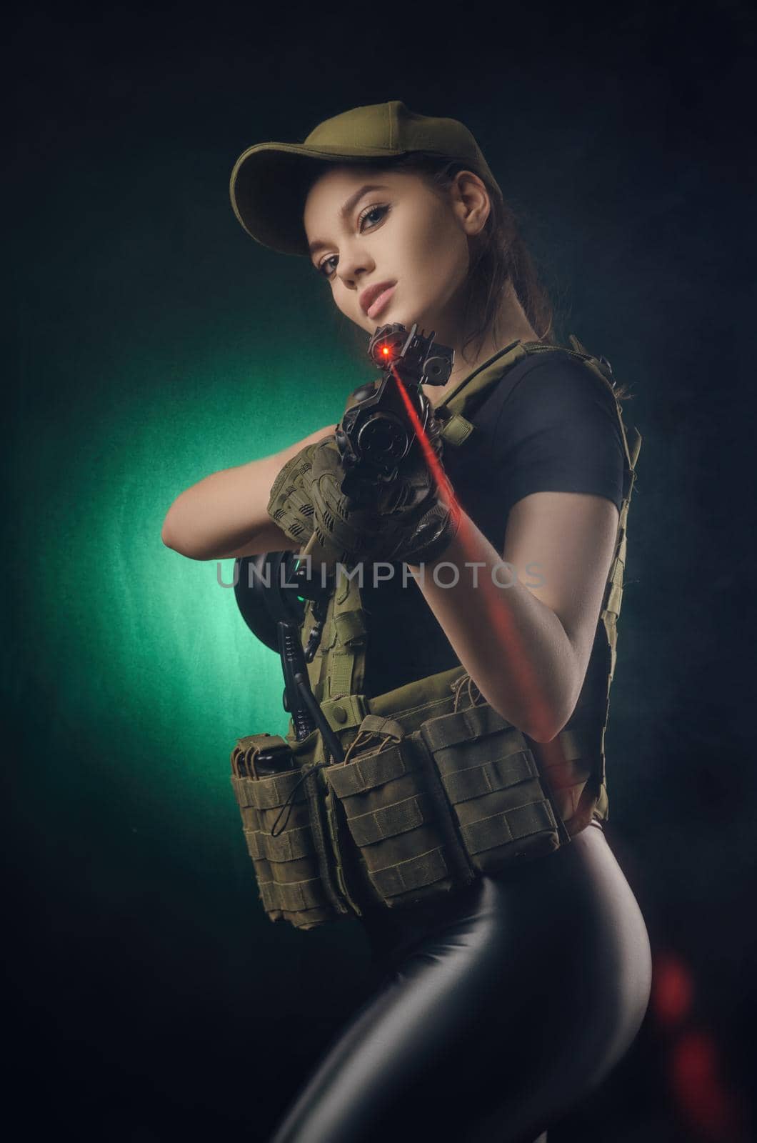 girl in military special clothes posing with a gun in his hands on a dark background in the haze