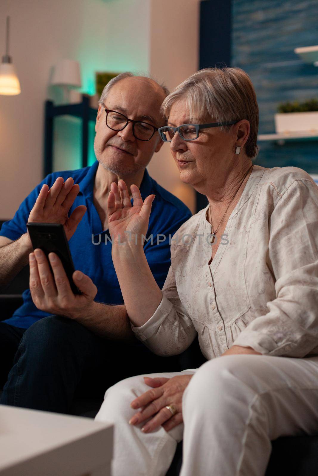 Retired man and woman chatting on video call conference by DCStudio