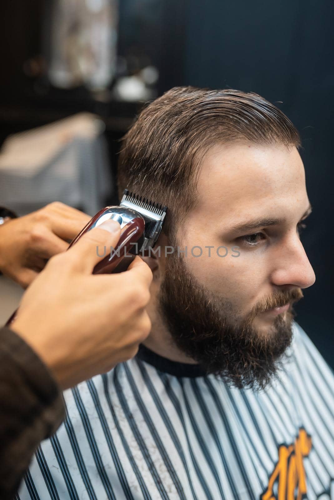 Men's hairstyling and haircutting with hair clipper in a barber shop or hair salon