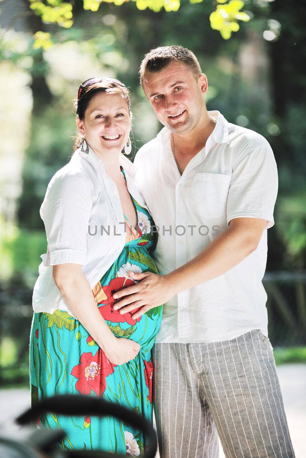Happy pregnant couple at beautiful sunny day in park by dotshock