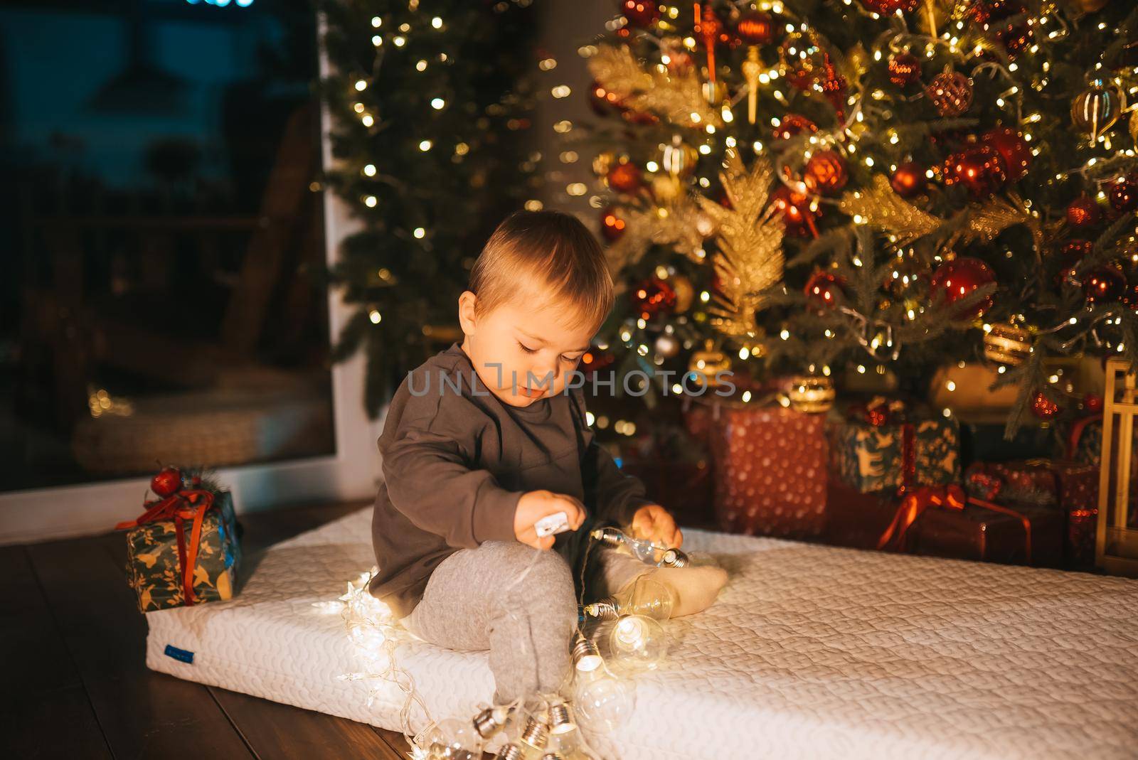 Child celebrating holidays near Christmas tree. New year and gifts. Magic.