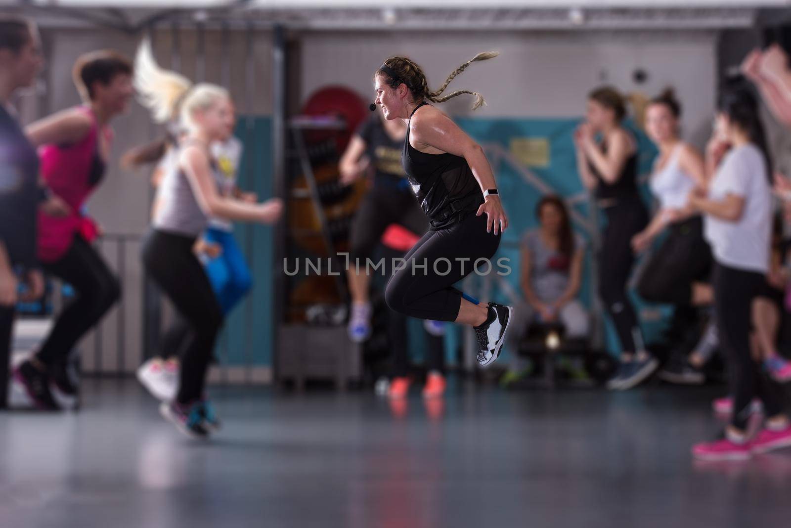 group of young healthy sporty women working out with instructor doing aerobics exercises in a fitness studio fitness, sport, training, gym and lifestyle concept