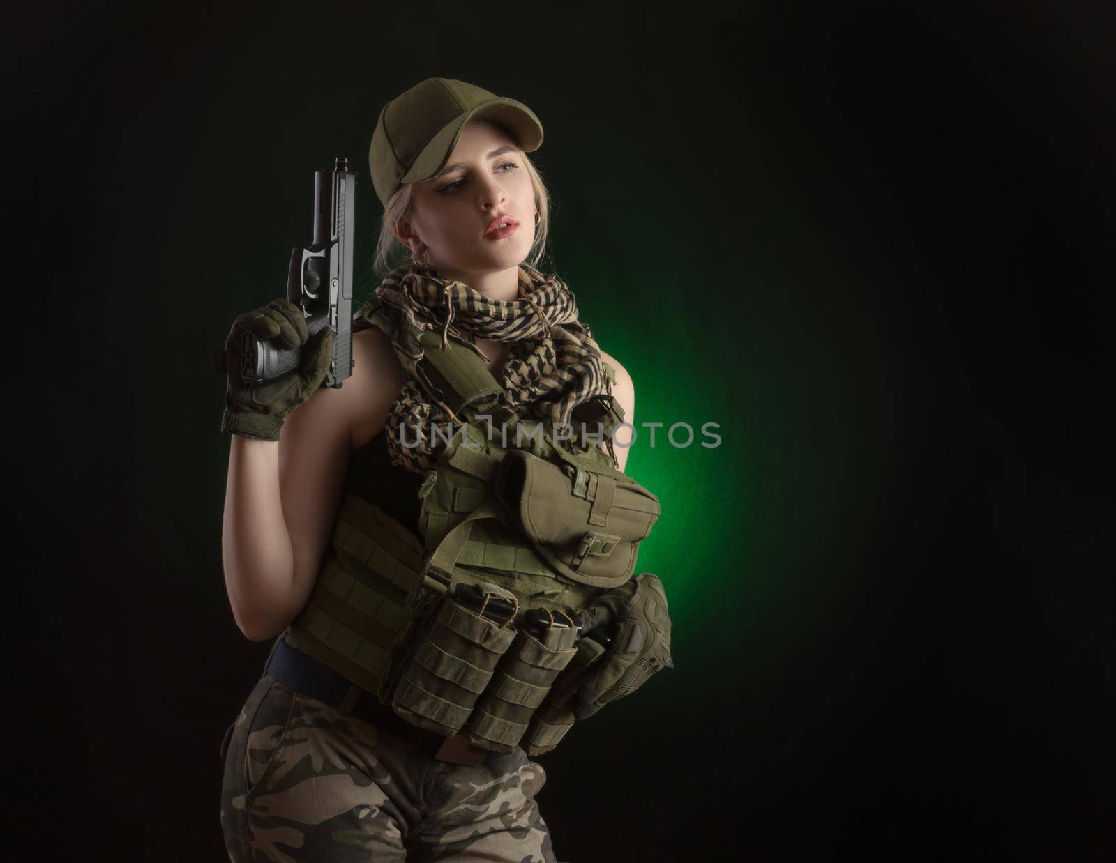 the girl in military special clothes posing with a gun in his hands on a dark background in the haze