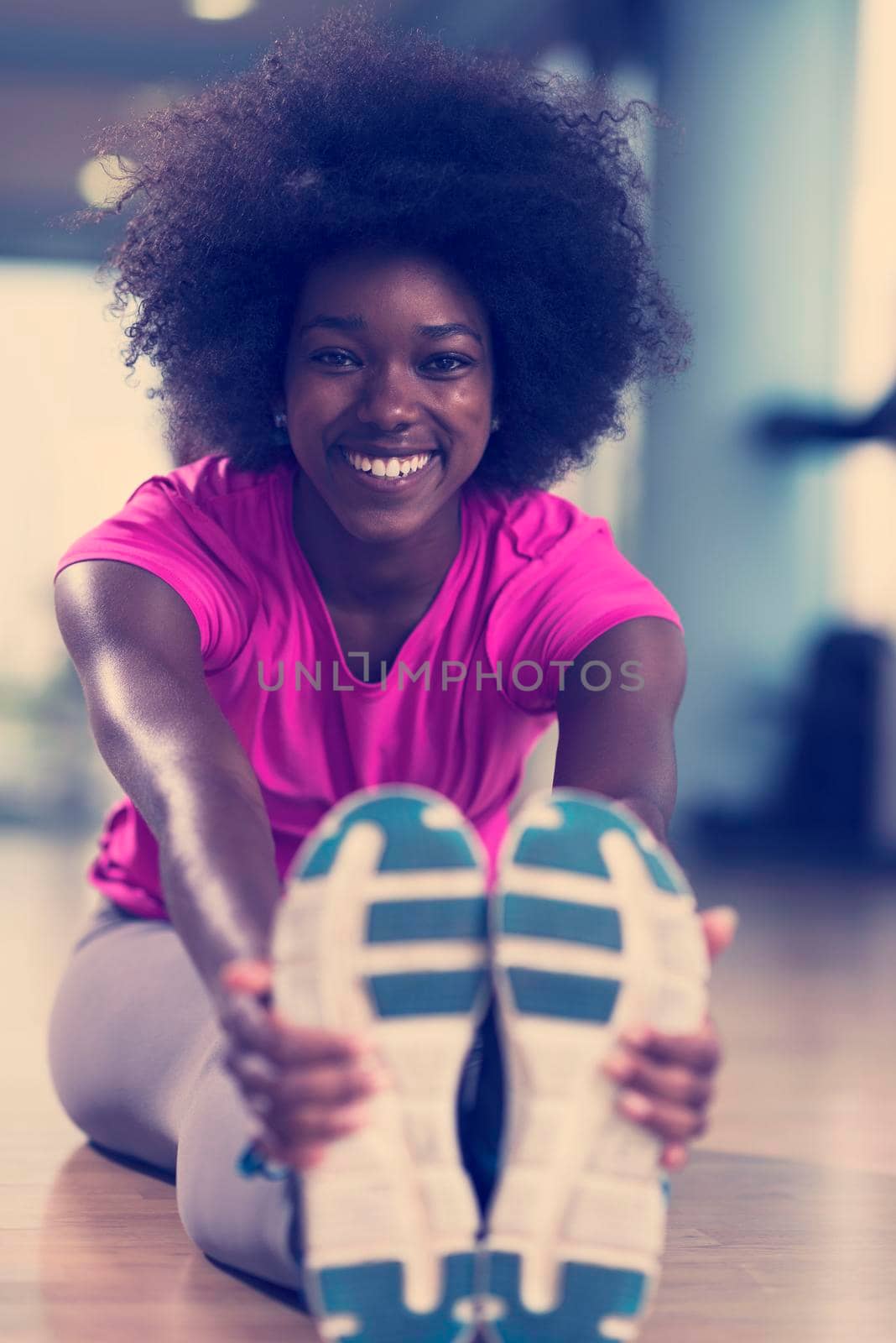 woman in a gym stretching and warming up before workout by dotshock